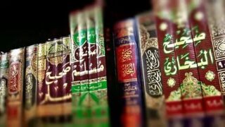 Row of ornate books with Arabic titles, various colors, and patterns on a shelf.